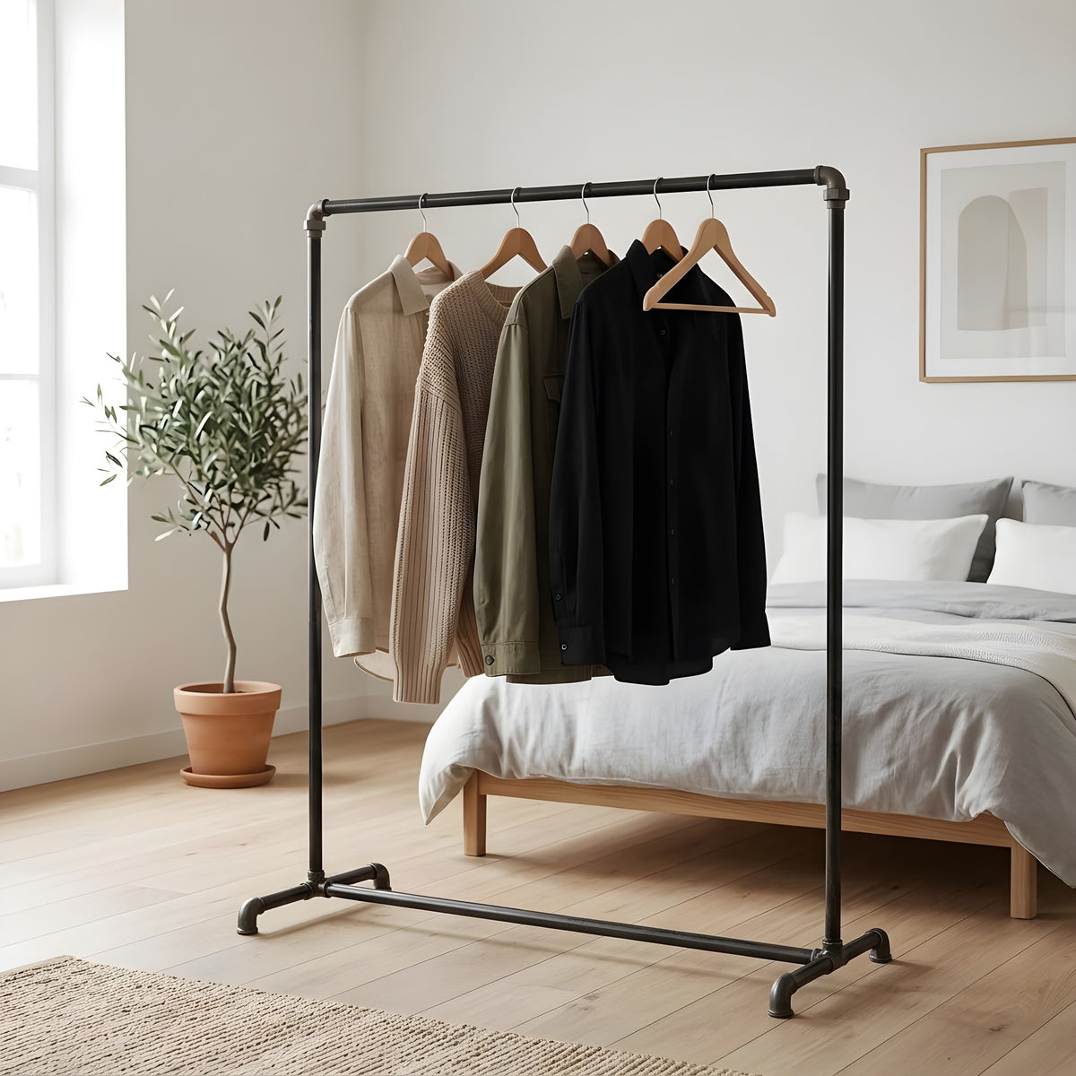 Industrieel kledingrek van zwarte loodgietersbuizen in een lichte slaapkamer, kleding op houten hangers