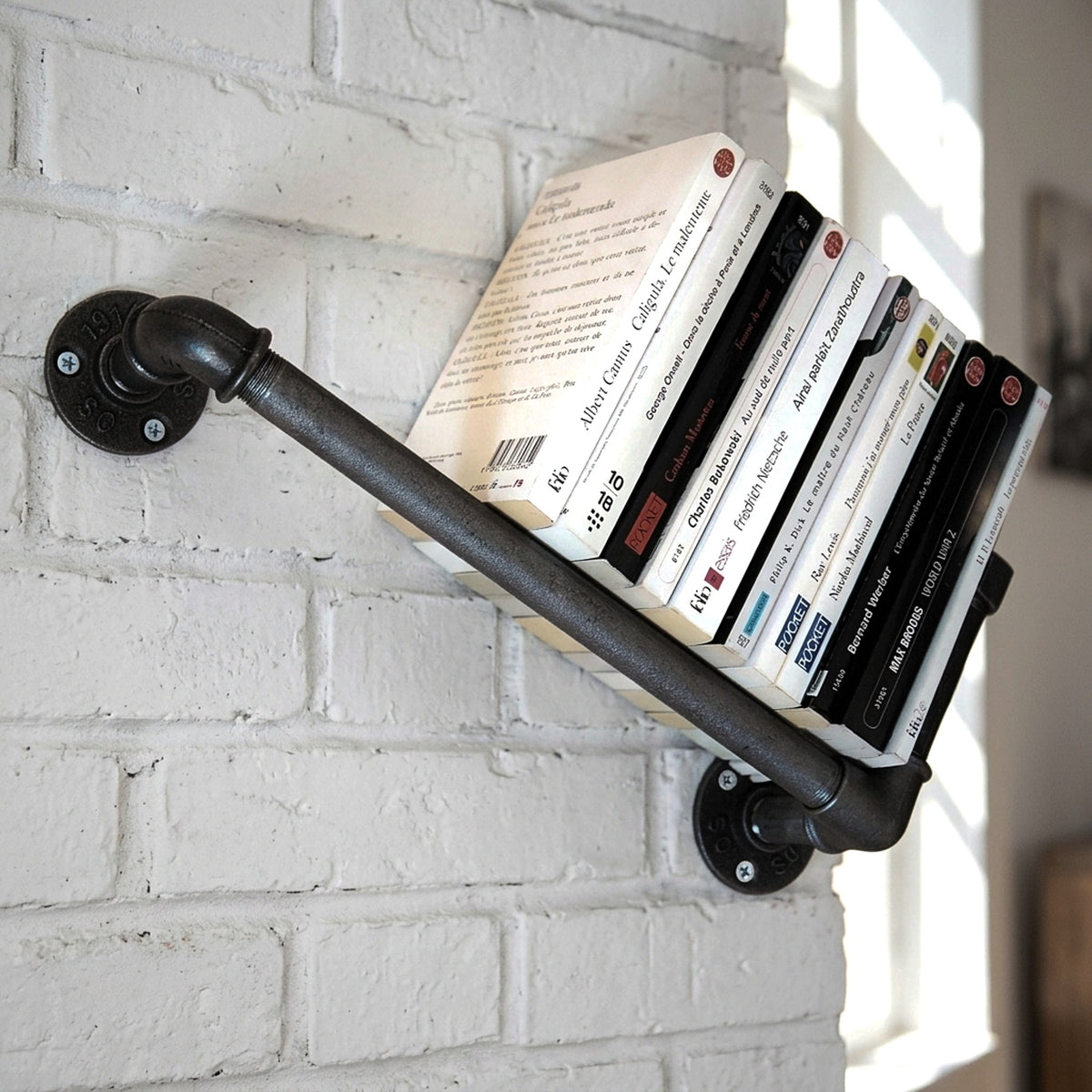 Gietijzeren wandboekenrek op een bakstenen muur met boeken, loftsfeer