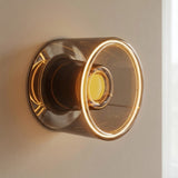 E27 led-donutlamp van rookglas, Ø 120 mm, brandend als wandlamp tegen een effen neutrale muur
