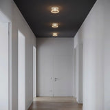 Drie E27 led-donutlampen van helder glas op een rij aan het plafond van een sobere gang