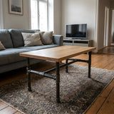 Salontafelonderstel, gietijzer en gelakt staal, H-frame Ø 34 mm, in een interieur onder een blad van licht massief eiken