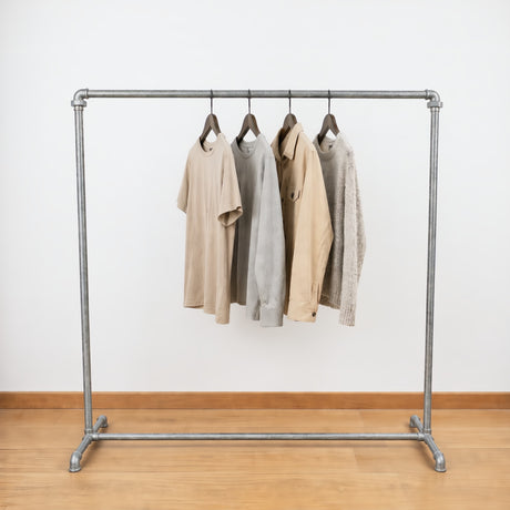 Industriële gegalvaniseerde kledingrek geladen met kleding aan hangers