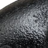 Close-up van de matte, korrelige zwarte lak op een gietijzeren fitting